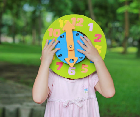 Child holding a play clock in the garden