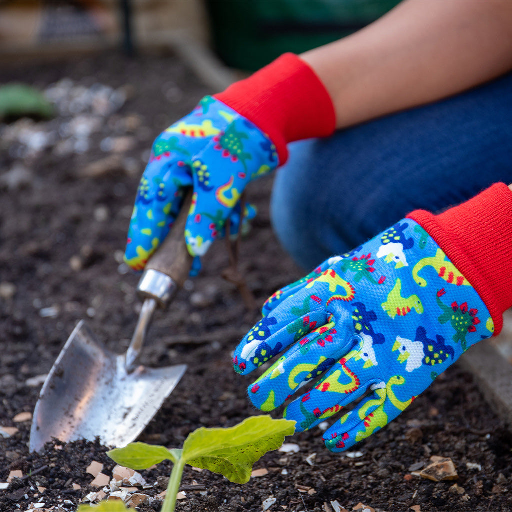 Child gardening wearing Kent and Stowe garden gloves for kids in blue with dinosaurs