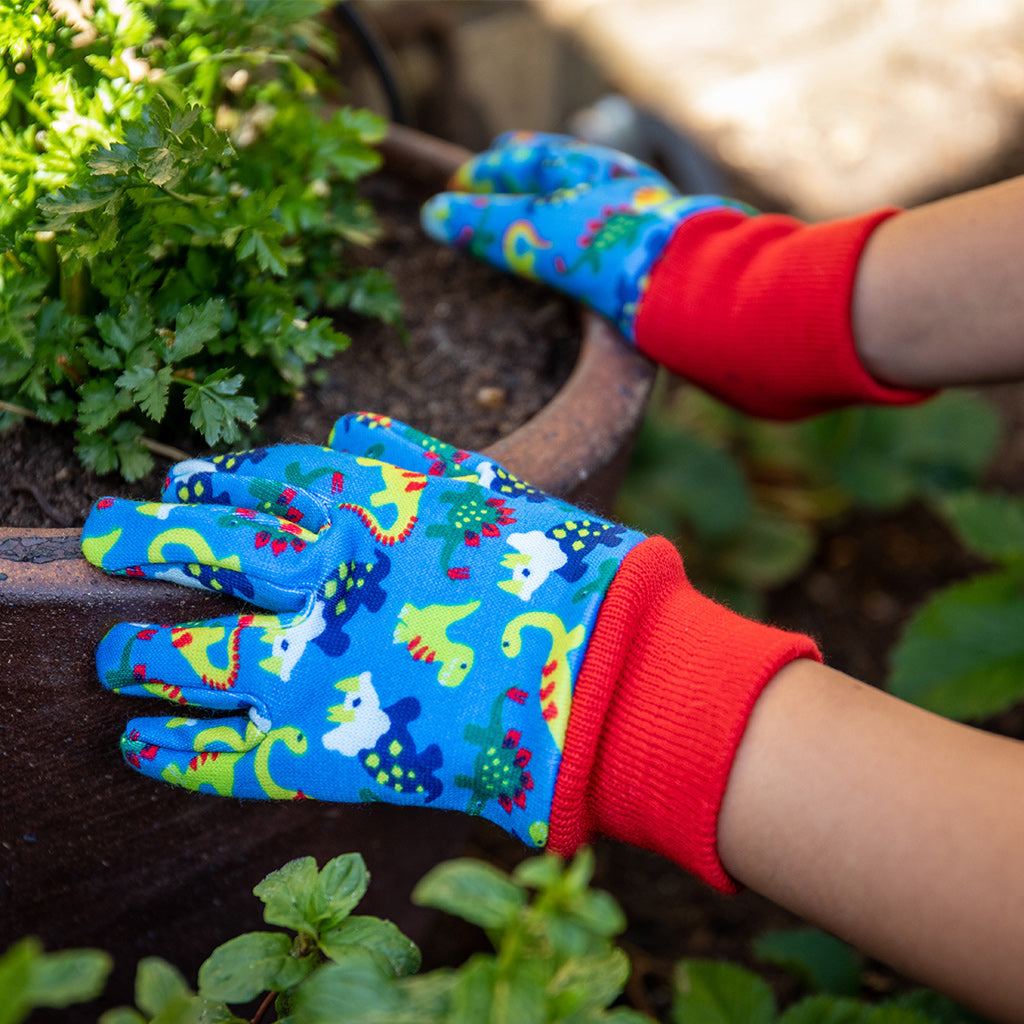 Child wearing Kent and Stowe gardening gloves for kids in blue with dinosaurs