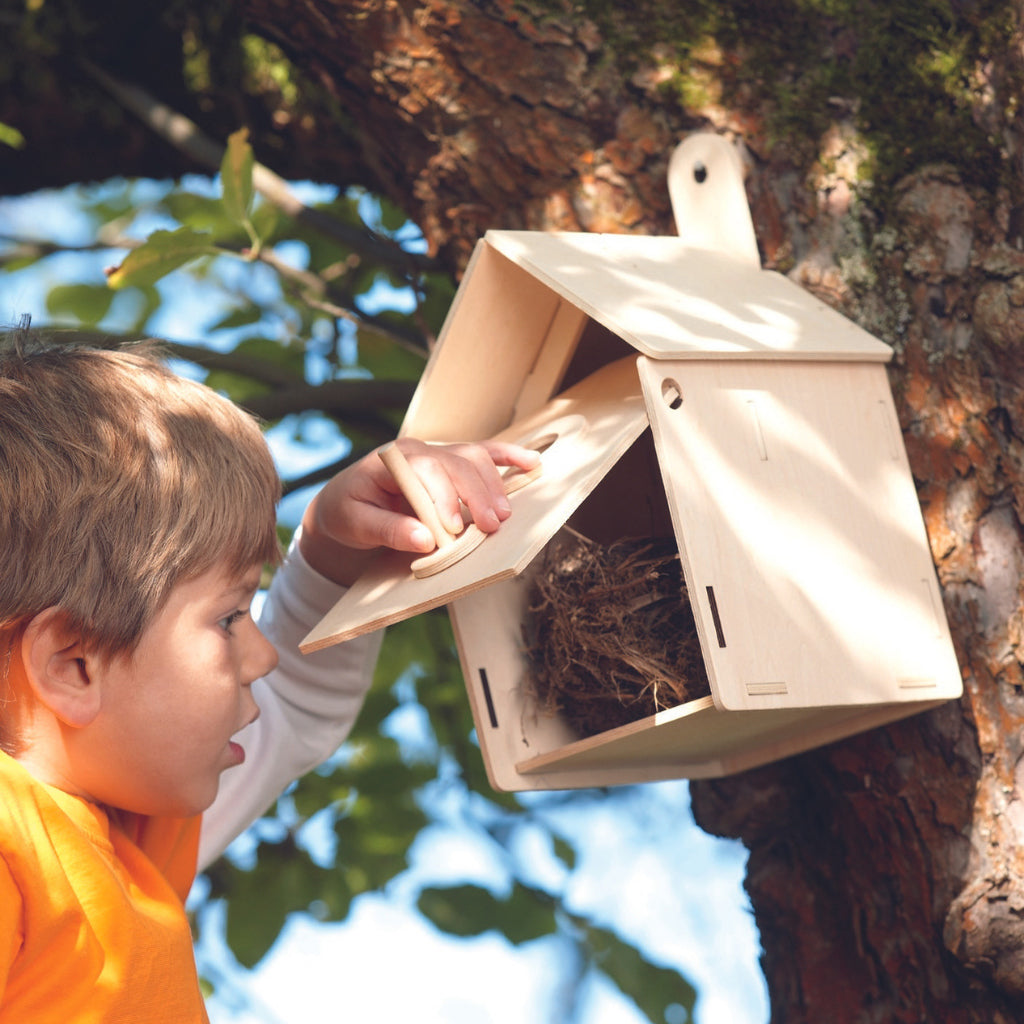 Little boy checking the HABA Nesting Box hanging on a tree