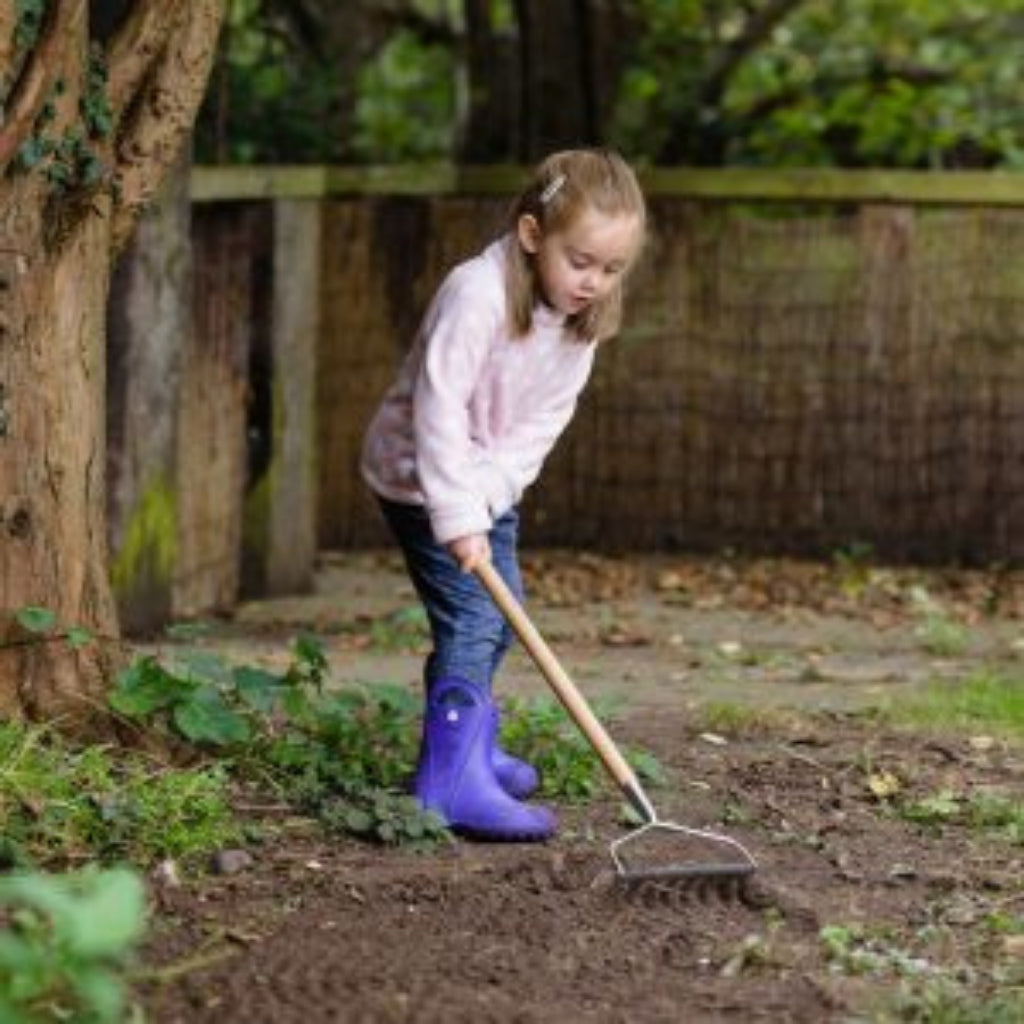 Girl using the Kent and Stowe garden Rake for children