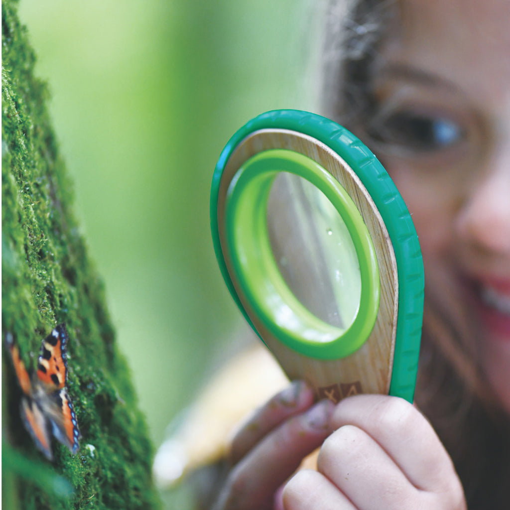 Girl using the childs magnifying glass from the Hape kids explorer kit to observe insects