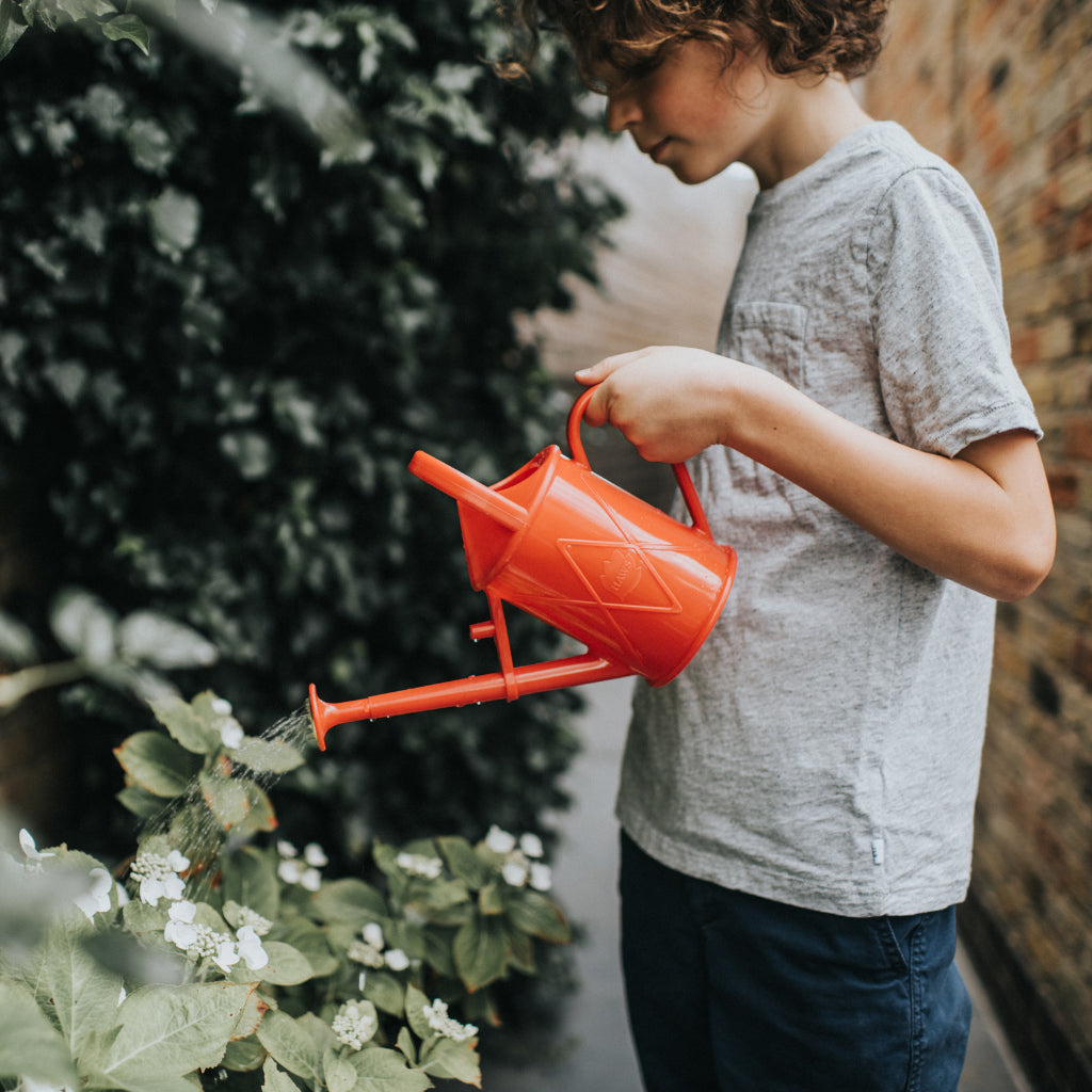 Child using Haws Bartley Burbler children watering can in red