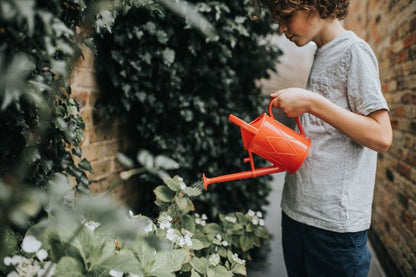 Child using the Haws Bartley Burbler children watering can in red